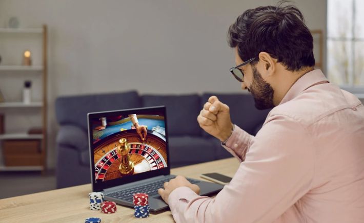 Счастливый игрок с выигрышем на экране казино